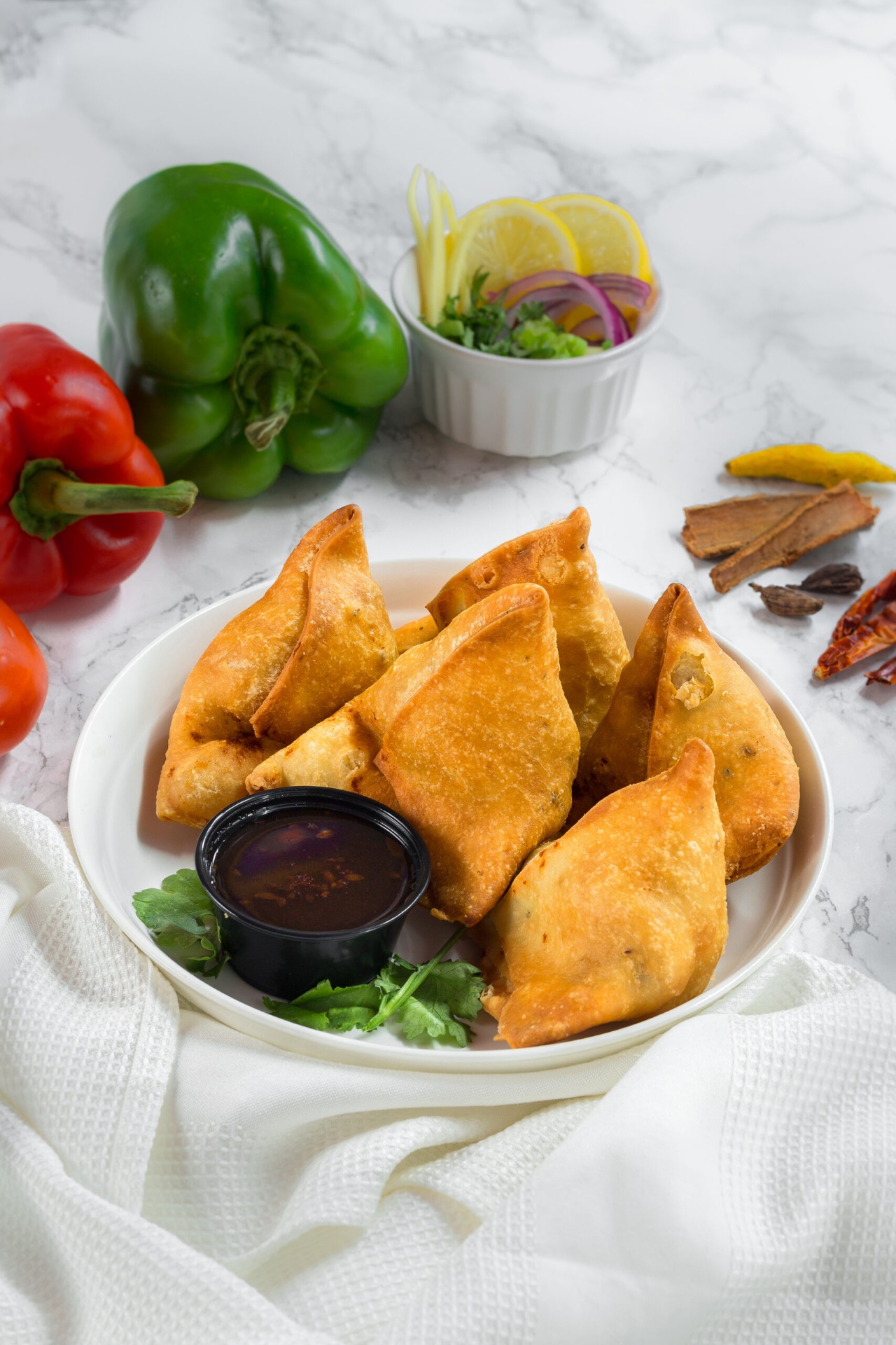Plate of beef samosas with tamarind dipping sauce, peppers and spices